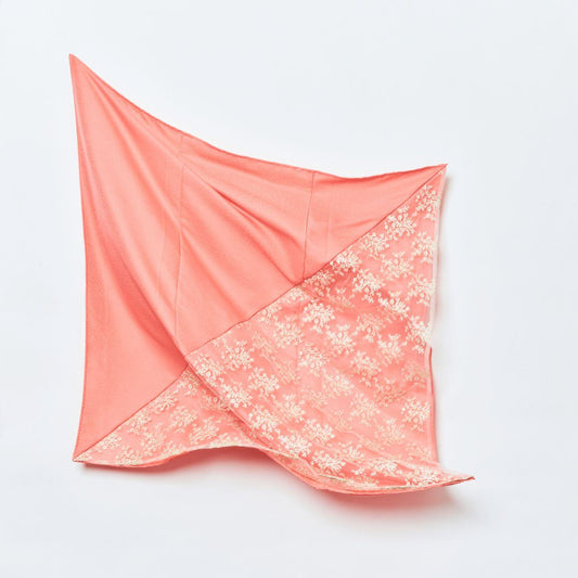 A close-up view of the coral pink Kimono silk headscarf, showcasing its graceful drape and the intricate craftsmanship of the repurposed artisanal textile.